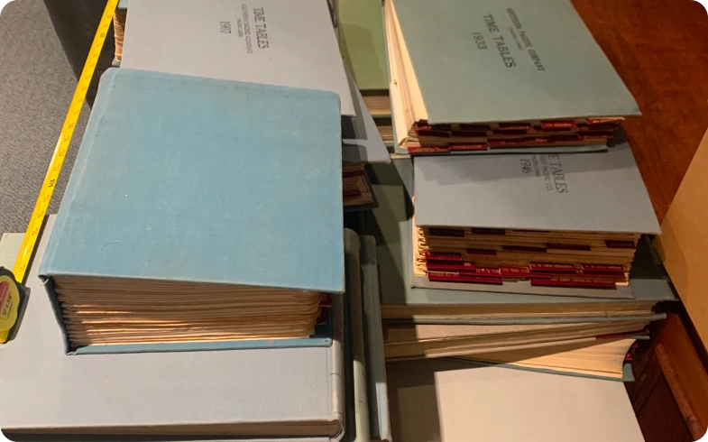 Stacked Southern Pacific timetable volumes from 1940s–1950s digitized by eRecordsUSA for California State Library